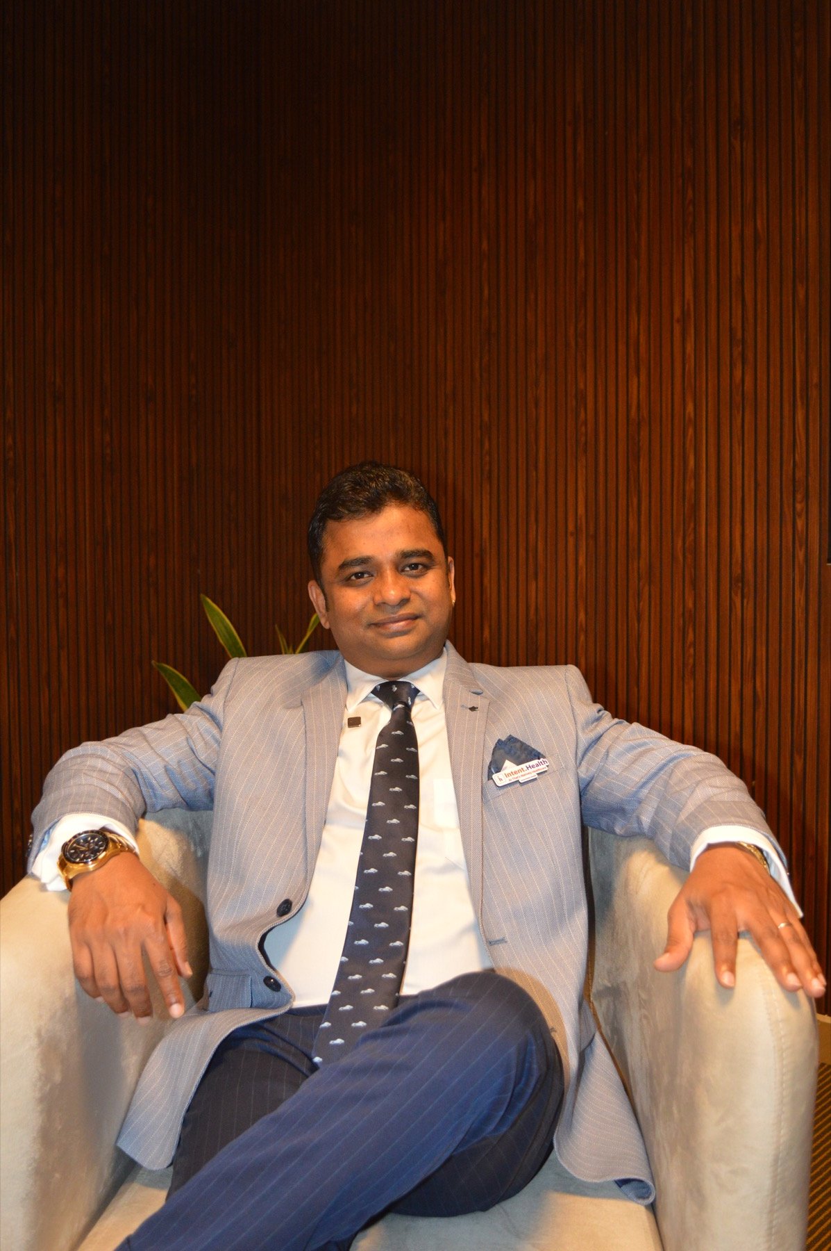 Arun Pillai seated in a light grey suit